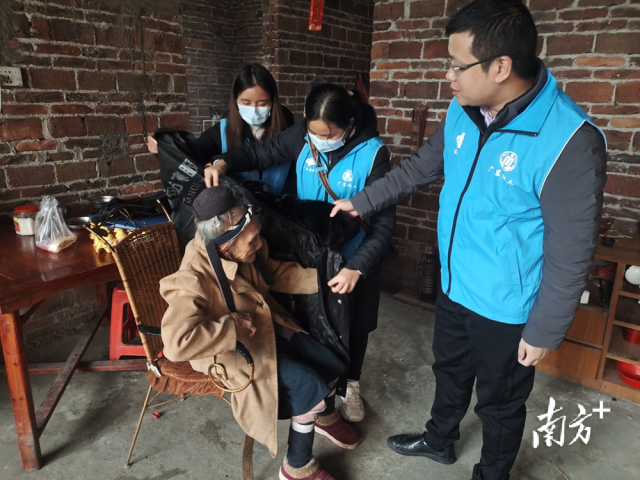 連南瑤族自治縣香坪鎮(zhèn)社工站為困難高齡老人送去御寒棉衣，并幫老人穿上棉衣。